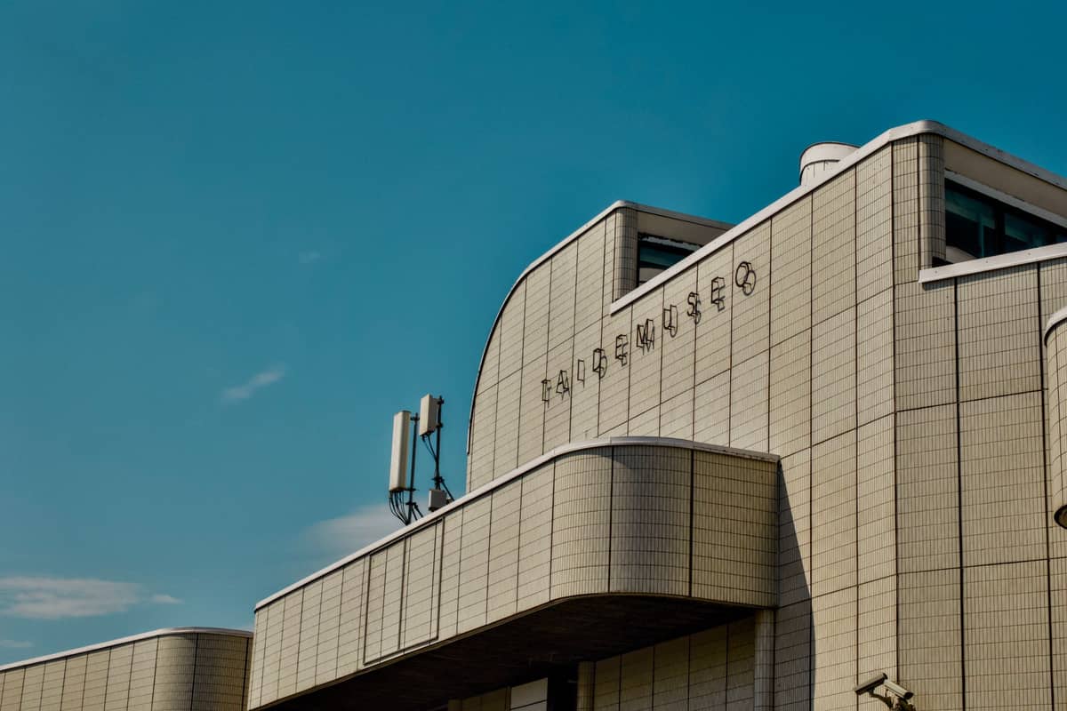 Exterior de um edifício moderno com a palavra 'TAIDEMUSEO' na fachada sob um céu azul claro.