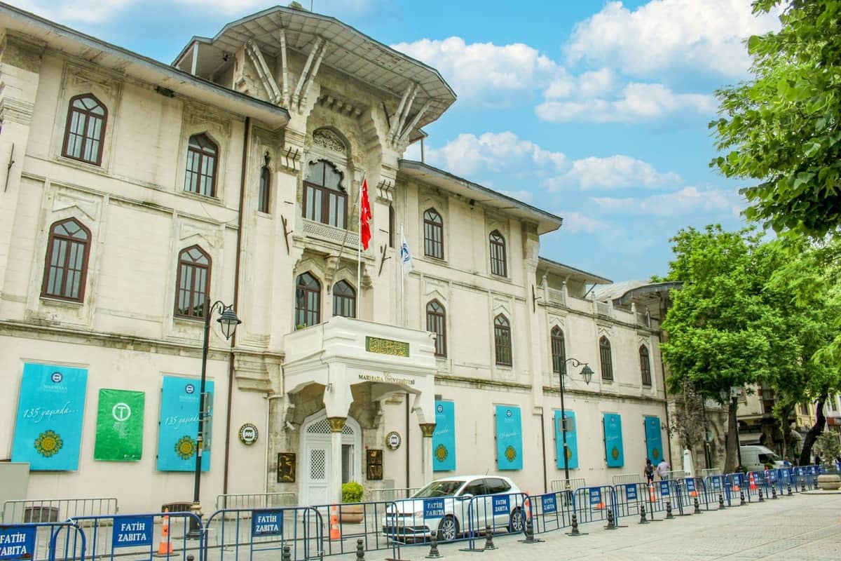 Exterior ornamentado del Museo de Arte Turco e Islámico de Estambul con fachada decorativa, bandera turca y pancartas del museo visibles.