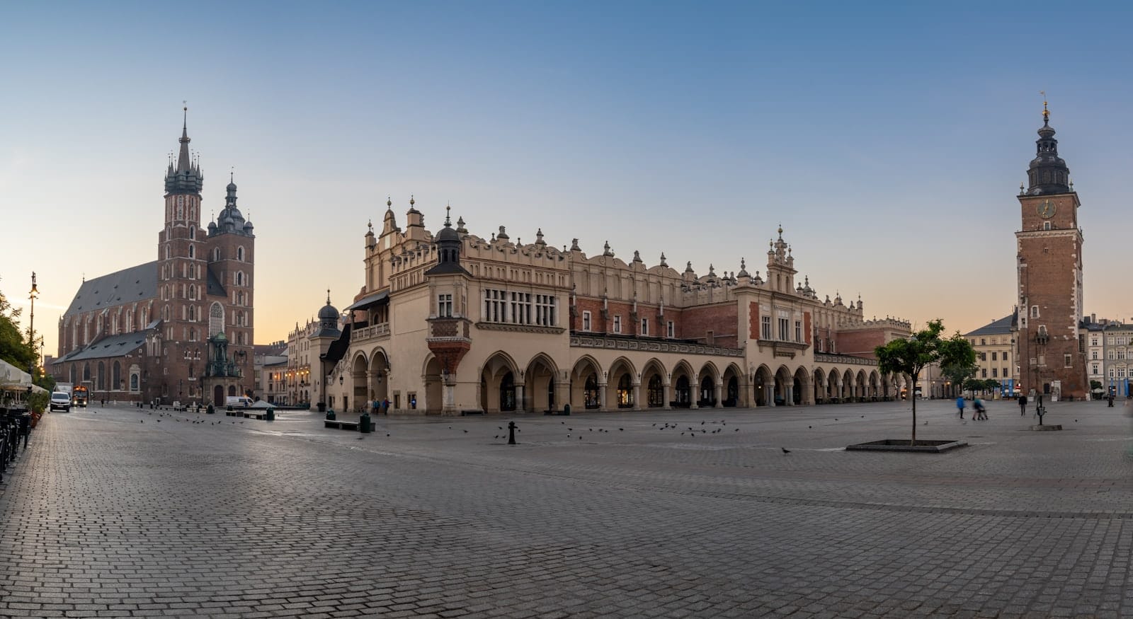 วิวพาโนรามาของจัตุรัสตลาดหลักของเมืองคราคูฟพร้อม Cloth Hall และมหาวิหาร St. Mary's ในยามรุ่งอรุณ สถานที่สัญลักษณ์ของพิพิธภัณฑ์ศิลปะ