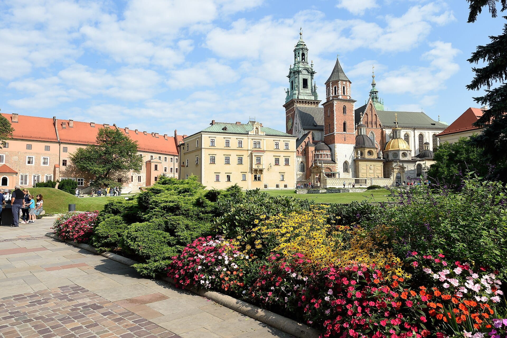 Wawel Hill ในเมือง Kraków ที่เห็นหอคอยของมหาวิหาร อาคารประวัติศาสตร์ และสวนดอกไม้หลากสีสันในวันที่แดดจัด
