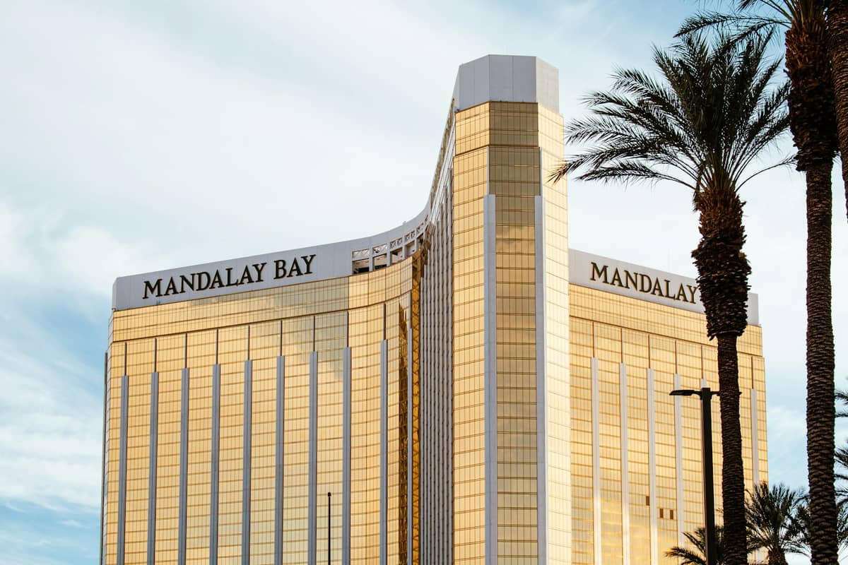 ภายนอกสีทองของ Mandalay Bay Resort and Casino ซึ่งเป็นที่ตั้งของพิพิธภัณฑ์สัตว์น้ำ Shark Reef มองเห็นต้นปาล์มใต้ท้องฟ้าสีฟ้า