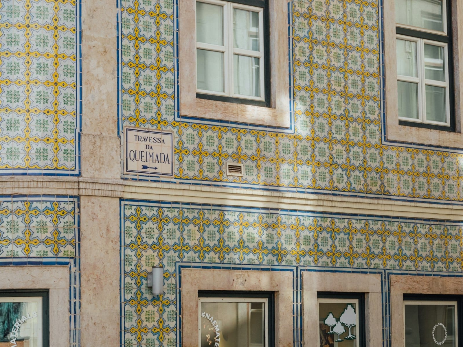 Coin de rue à Lisbonne recouvert d'azulejos traditionnels, avec fenêtres et enseigne du bâtiment en plein jour