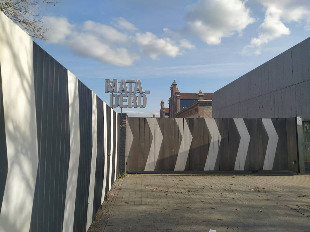 Cancello d'ingresso del Matadero Madrid con insegna in grassetto ed elementi di design grafico moderno sotto un cielo azzurro.