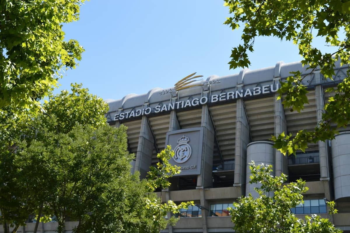 Vista esterna dello stadio Estadio Santiago Bernabéu a Madrid incorniciato da alberi verdi in una giornata di sole limpida