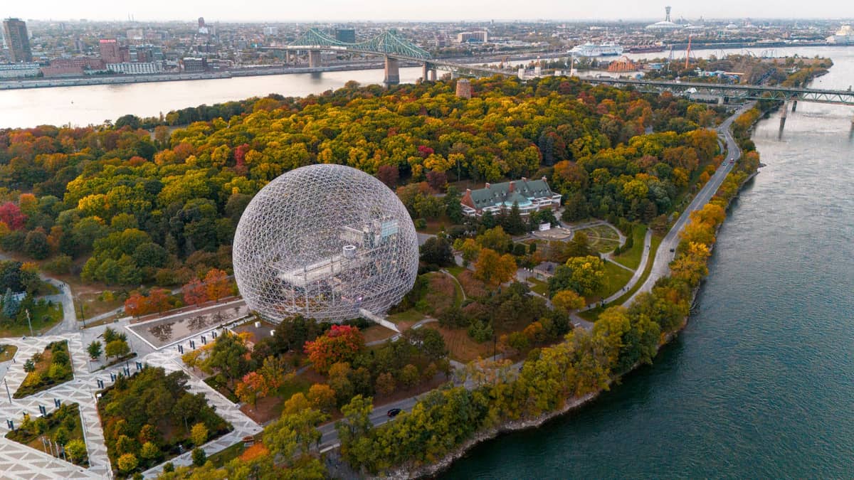Luftaufnahme des Biosphère-Museums auf der Île Sainte-Hélène in Montreal, umgeben von Herbstbäumen mit der Stadt und dem Fluss im Hintergrund.