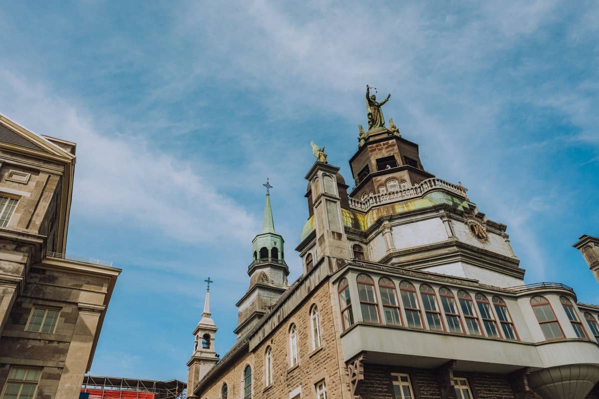 Edificio histórico con torres ornamentadas y estatuas bajo un cielo azul, reminiscente de la arquitectura patrimonial de Montréal y los museos del Vieux-Montréal.