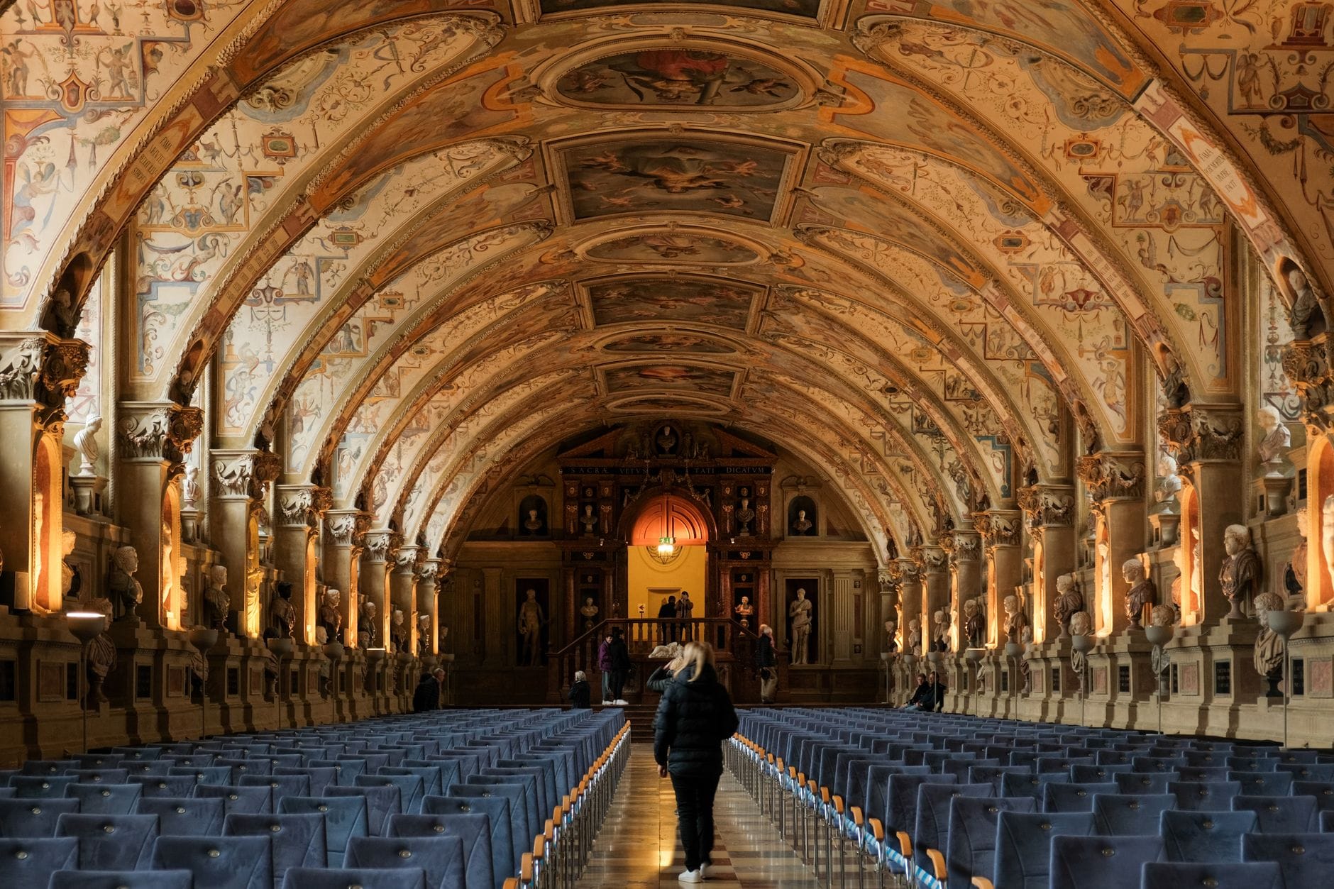 มุมมองกว้างของ Antiquarium ใน Residenz เมือง Munich แสดงให้เห็นเพดานโค้งประดับประดา รูปปั้น และแถวเก้าอี้ในภายในอาคารประวัติศาสตร์