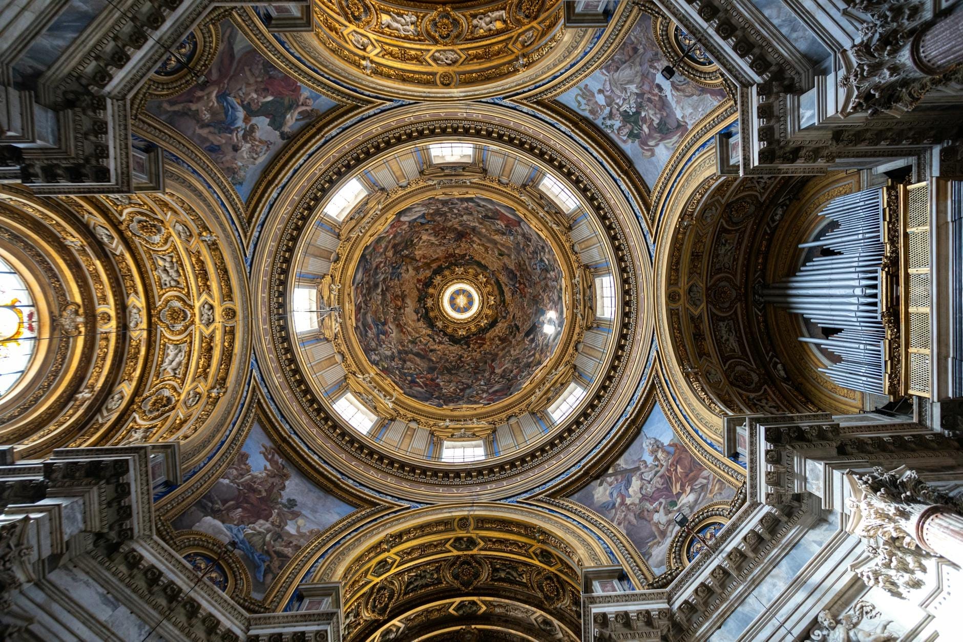 Cúpula e teto barrocos ornamentados com detalhes dourados e afrescos coloridos no interior de uma grande capela ou museu-palácio napolitano.
