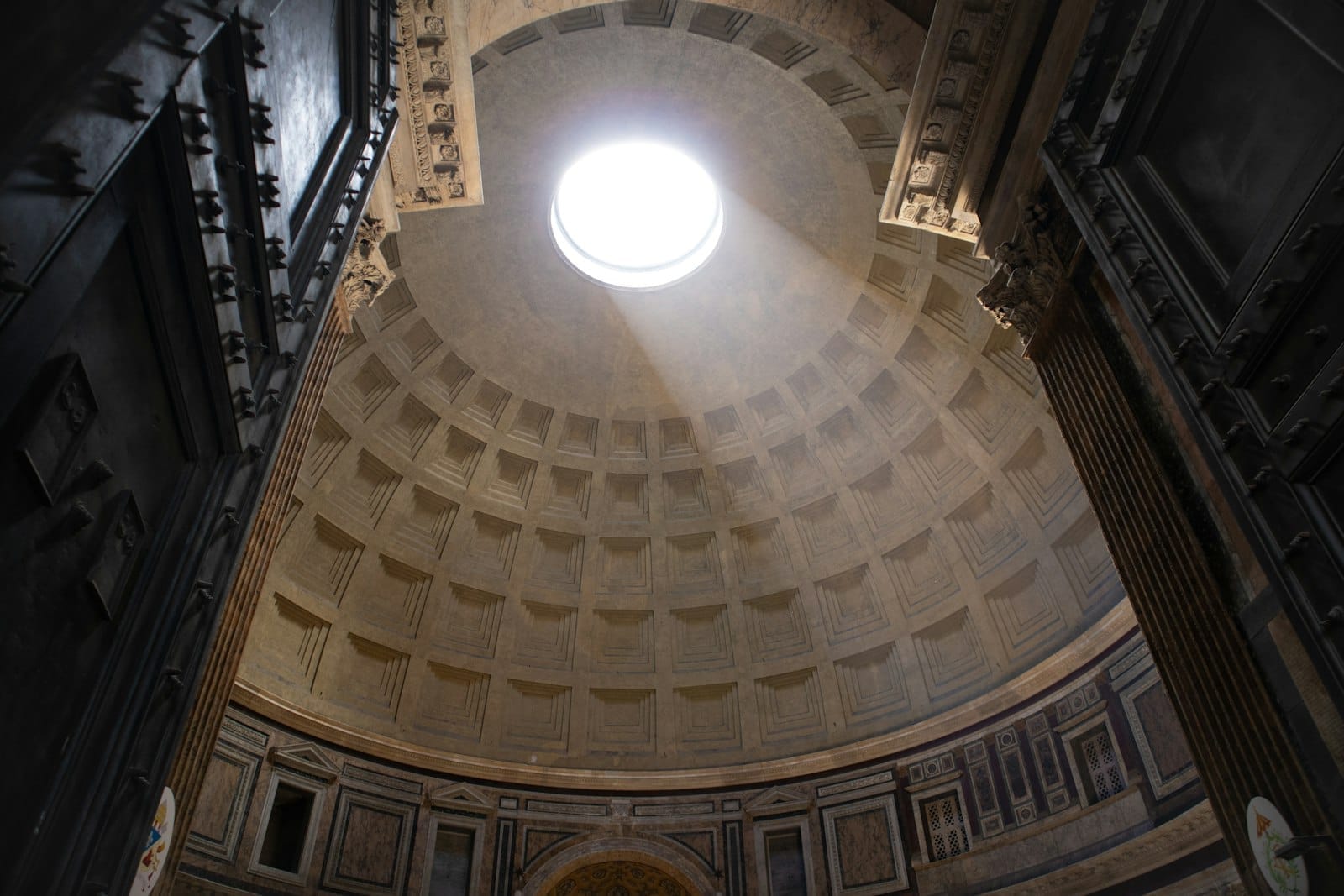 Interior of the Pantheon in Rome with sunlight streaming through the oculus, highlighting ancient Roman architectural features.