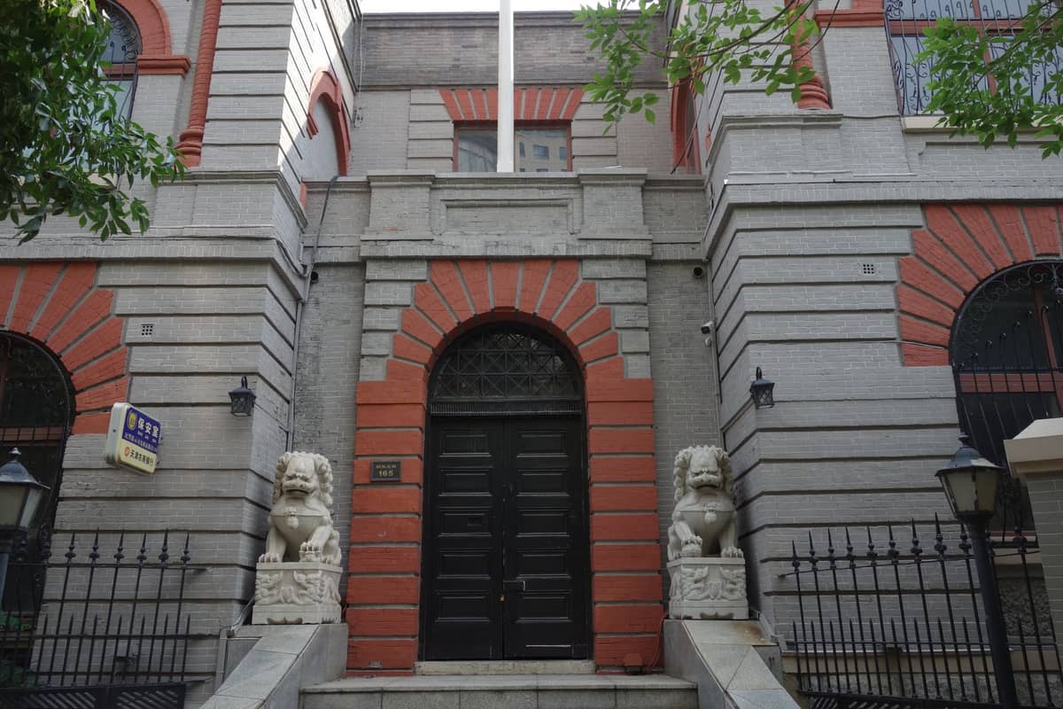 Façade d'un petit bâtiment de musée à l'aspect historique à Shanghai, flanqué de statues de lions en pierre et de rampes en fer, évoquant une institution spécialisée ou de niche.