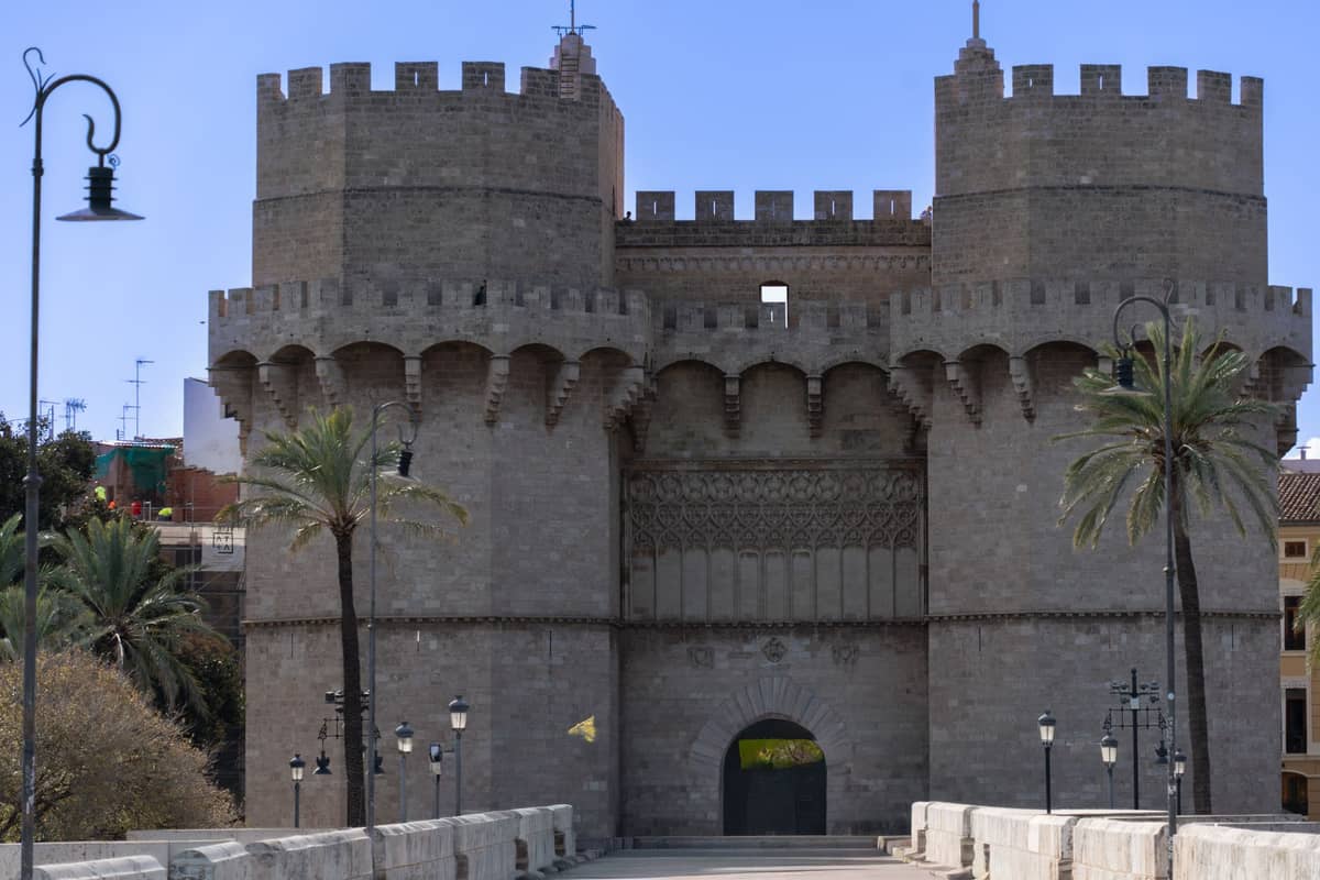 Blick auf die Torres de Serranos, ein markantes historisches Steintor mit zwei Türmen und Palmen, in Valencia, Spanien.