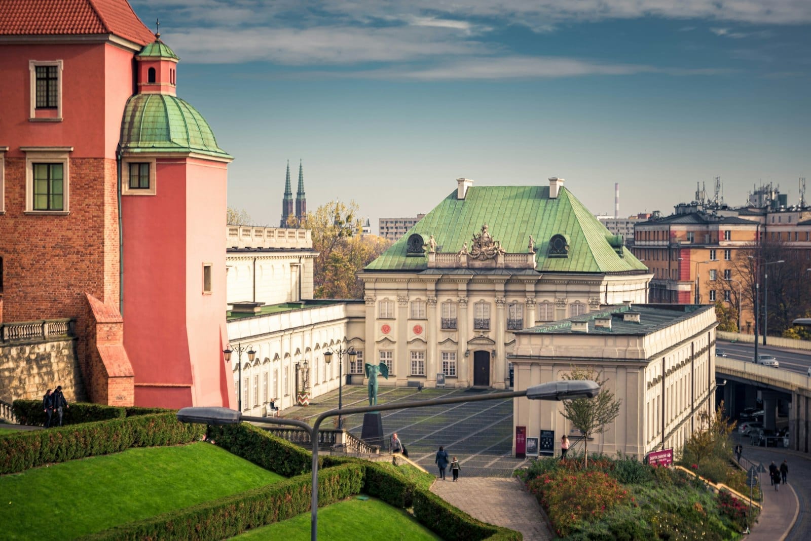 Vista dos jardins históricos do Castelo Real de Varsóvia e do palácio barroco sob um céu azul, perfeito para explorar os melhores museus da cidade.