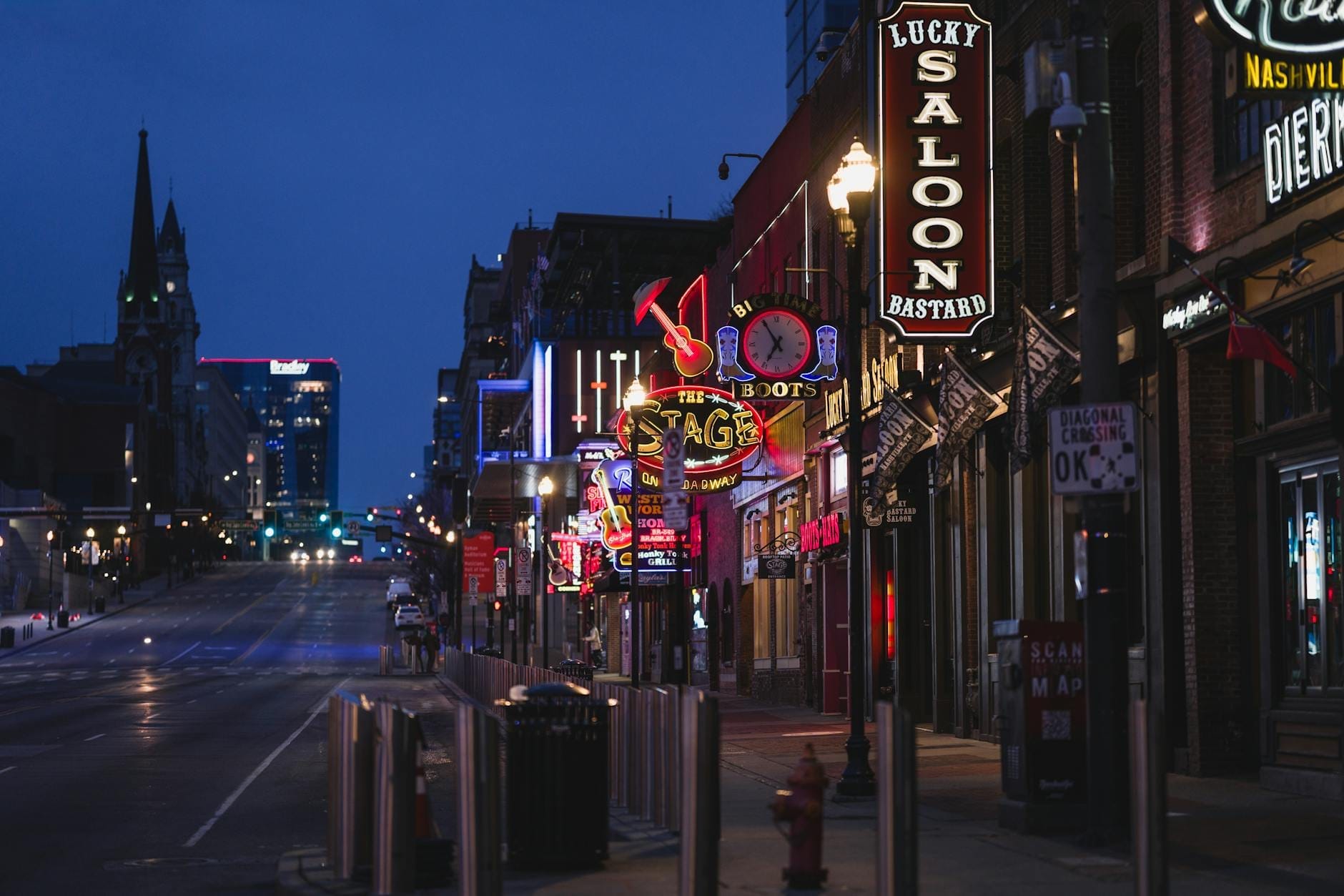 Vista nocturna del Lower Broadway de Nashville con letreros de neón de bares famosos y locales de música, incluyendo The Stage y Lucky Bastard Saloon.