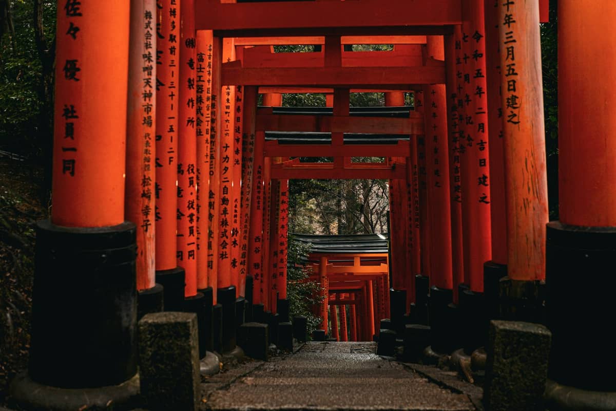 Pathway lined with iconic red torii gates at Fushimi Inari Taisha, one of Kyoto's most famous and ancient UNESCO-listed Shinto shrines.