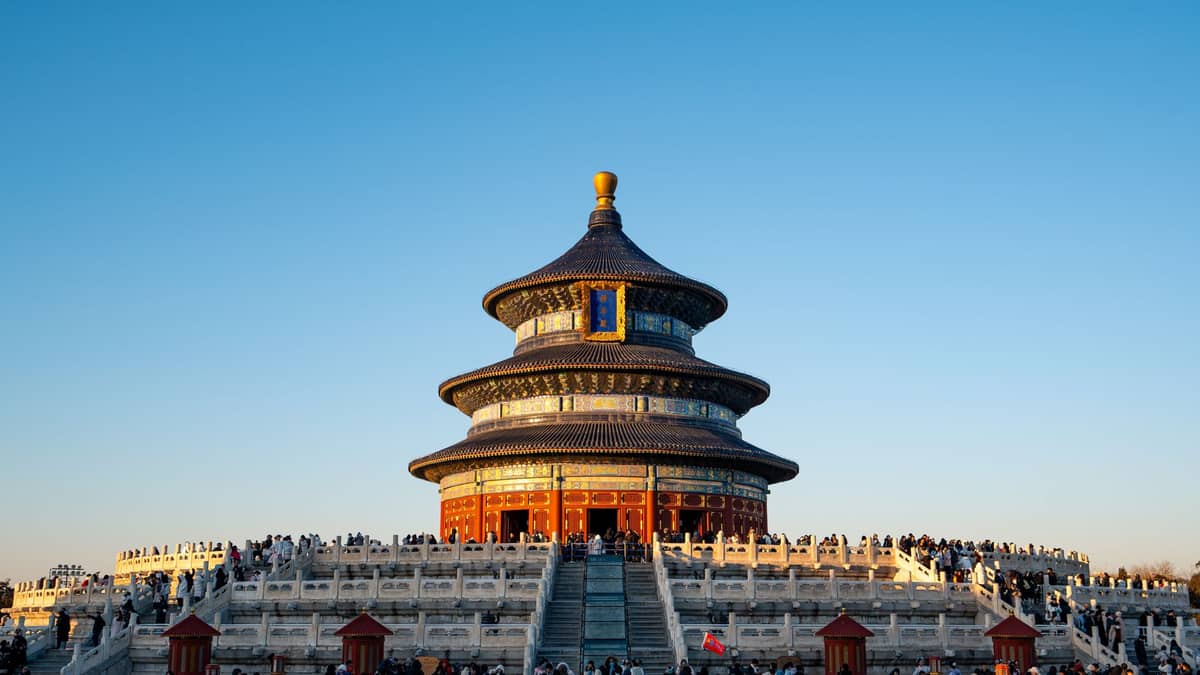Vista amplia del Salón de Oración por las Buenas Cosechas en el Templo del Cielo de Beijing, con multitudes y cielo azul, mostrando su estructura circular escalonada sobre terrazas de mármol elevadas.