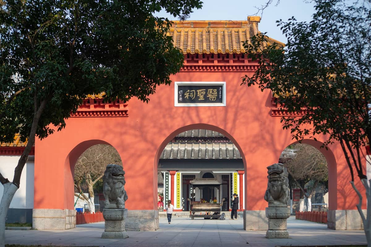 Vista frontale del Tempio Confuciano di Shanghai con cancello rosso, archi, leoni di pietra e cortile interno visibile di giorno.