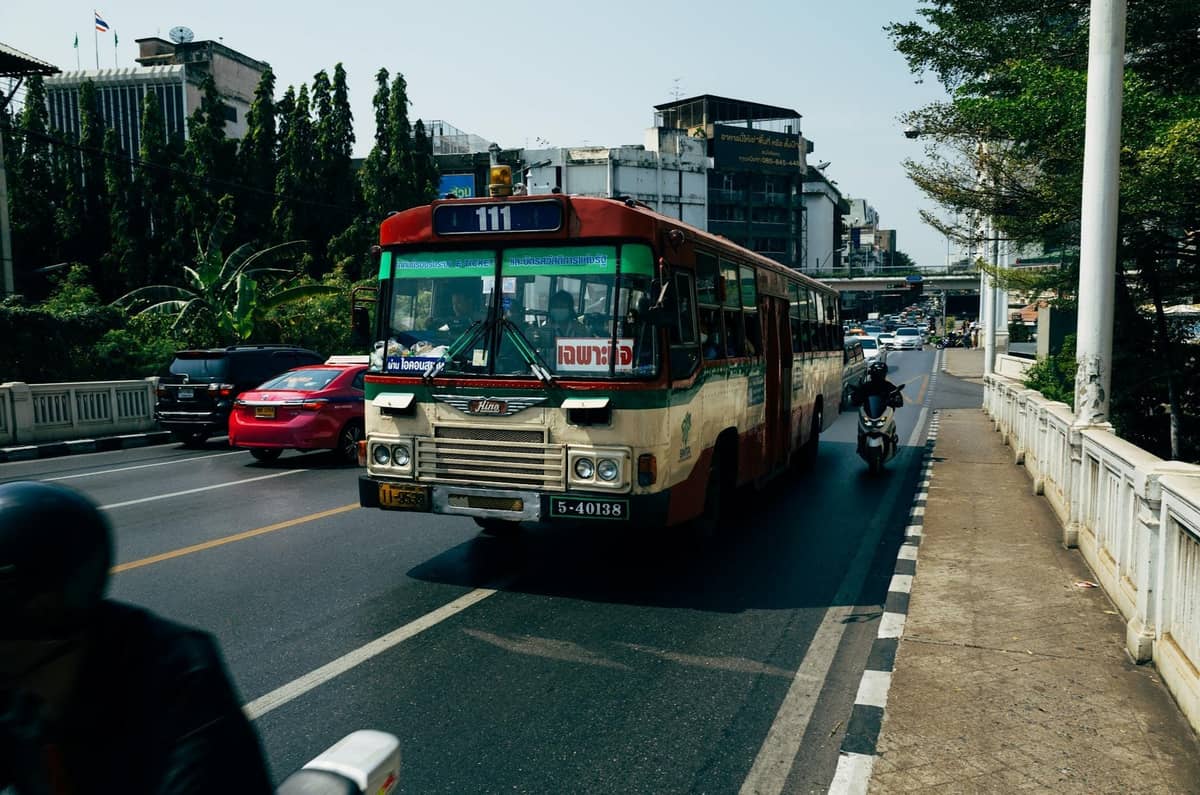 Ônibus público em uma rua de Bangkok com trânsito, mostrando opções de transporte local na cidade