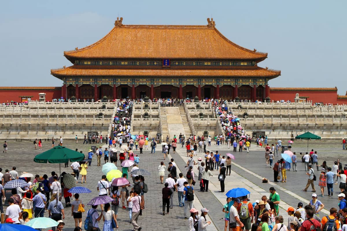Weitblick auf die Verbotene Stadt in Peking mit großen Menschenmengen, die unter einem klaren Himmel auf die Halle der Obersten Harmonie zugehen.