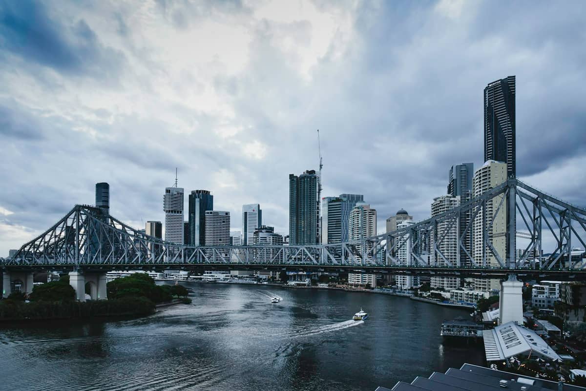 Skyline von Brisbane mit der Story Bridge, dramatischen Gewitterwolken und Booten auf dem Brisbane River, die eine sommerliche Atmosphäre hervorrufen.
