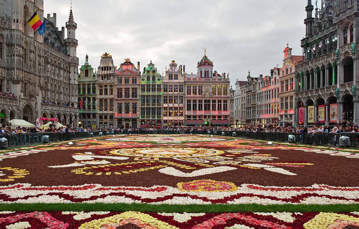 Multidões se reúnem ao redor do grande e colorido evento do Tapete de Flores de Bruxelas na Grand Place, cercada por históricas casas de guildas e edifícios da cidade.