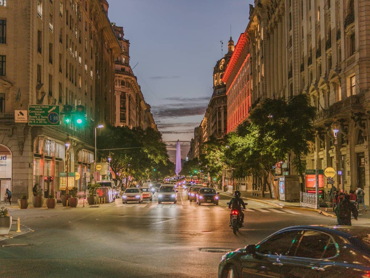 วิวยามเย็นของ Avenida Diagonal Norte ในบัวโนสไอเรส พร้อมการจราจรที่คึกคัก อาคารประวัติศาสตร์ และ Obelisco ที่มองเห็นได้ในระยะไกล