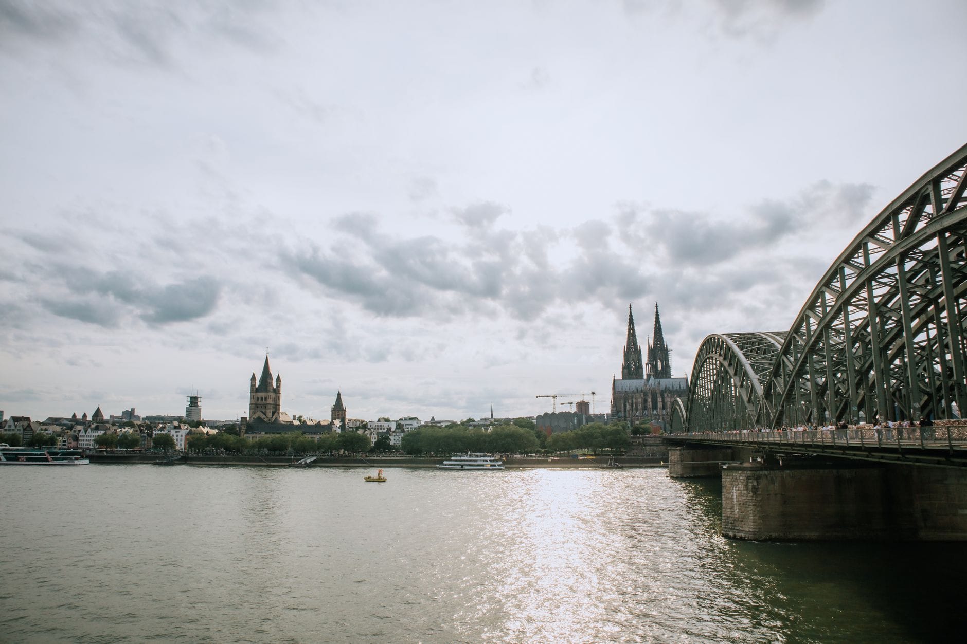 วิวกว้างของเส้นขอบฟ้าเมือง Cologne พร้อมแม่น้ำ Rhine สะพาน Hohenzollern และมหาวิหาร Cologne ใต้ท้องฟ้ามีเมฆ