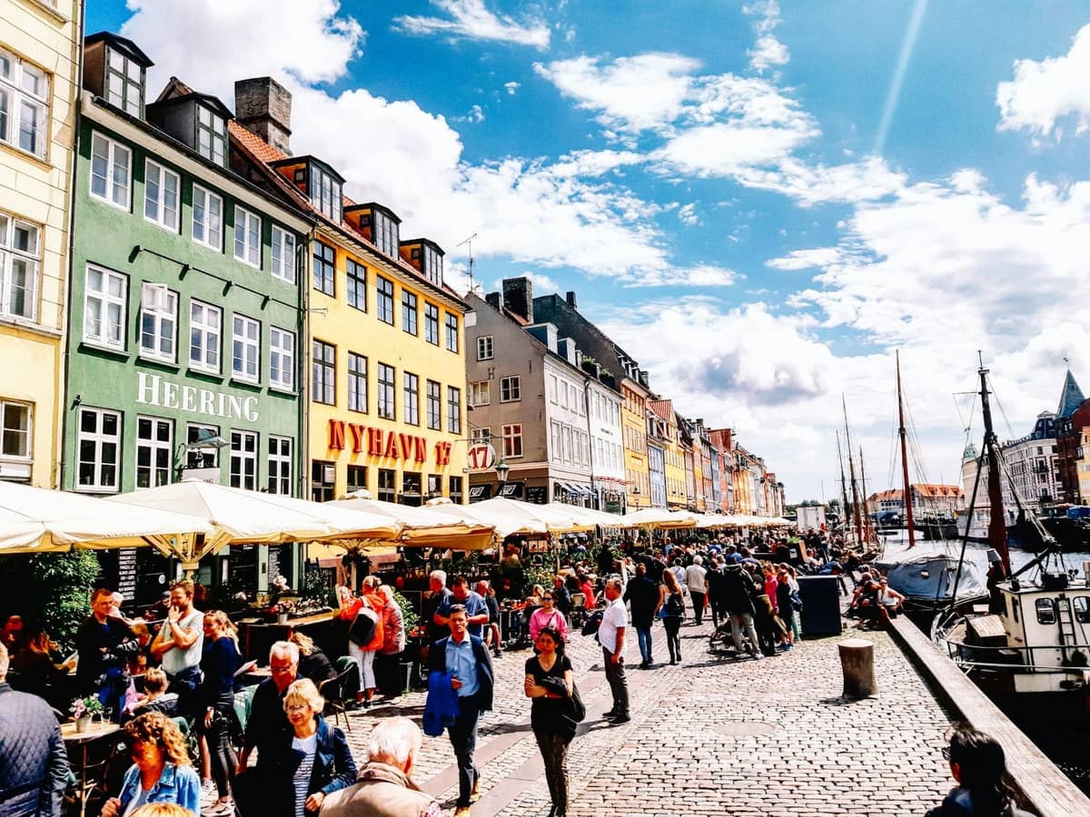 Des foules profitent des restaurants en plein air et de l'animation le long du canal Nyhavn par une ensoleillée journée d'été à Copenhague.