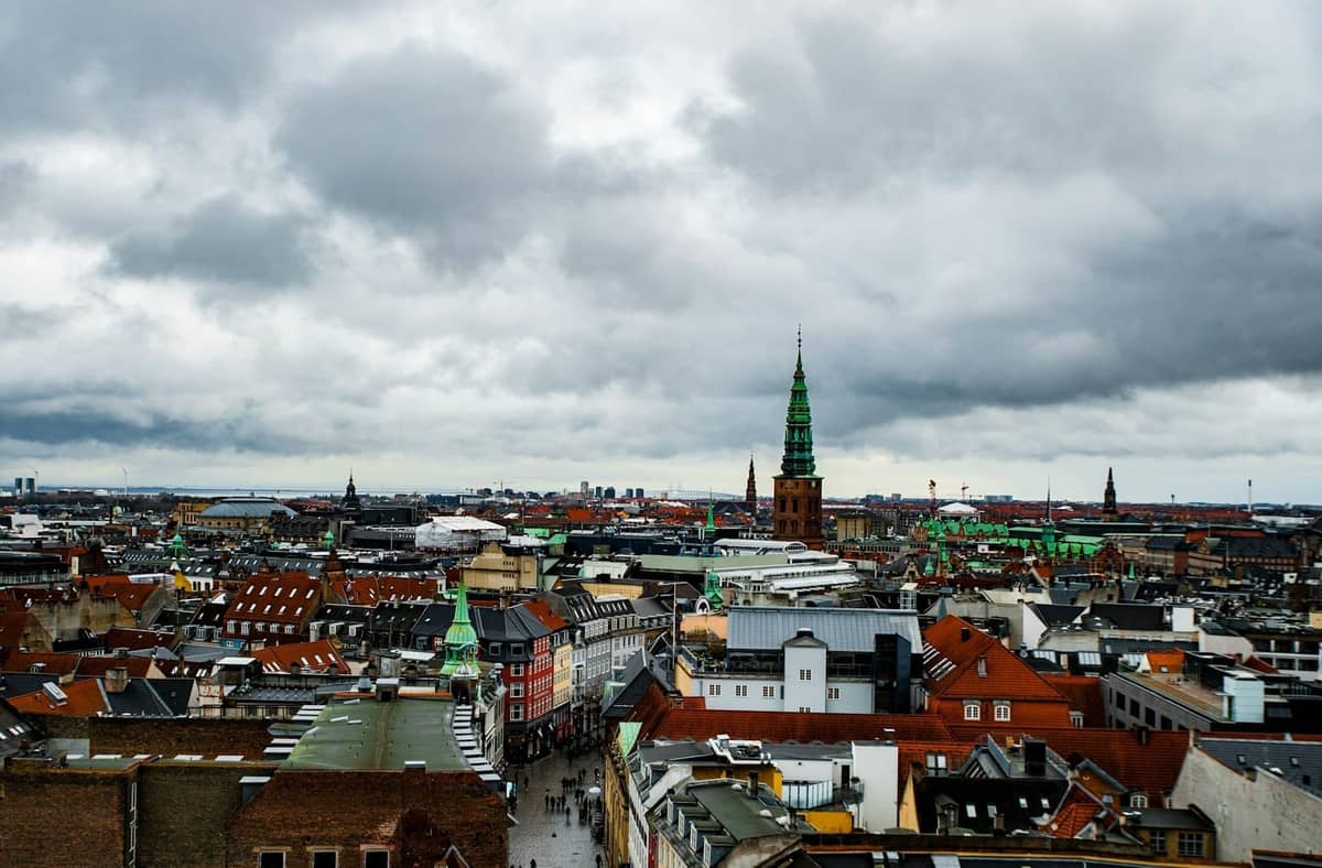 Ciel couvert au-dessus du paysage urbain de Copenhague avec des toits en briques et des clochers d'église, illustrant le climat tempéré et typiquement nuageux de la ville.
