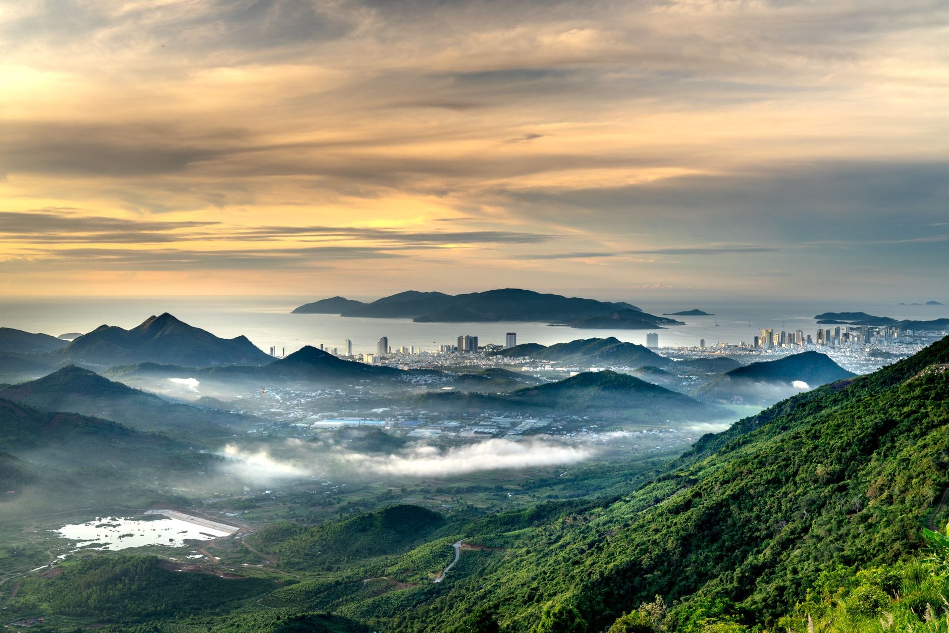 วิวพาโนรามาของเมืองดานังจากภูเขา พร้อมหมอกปกคลุมทิวทัศน์และท้องฟ้าสงบยามรุ่งอรุณหรือยามเย็น