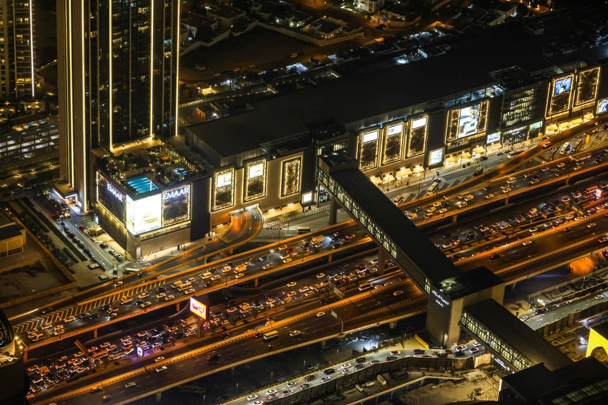 Nächtliche Luftaufnahme eines belebten Einkaufszentrums in Dubai mit beleuchtetem Außenbereich und starkem Verkehr, das während der Veranstaltungssaison ein bedeutendes Einzelhandelszentrum zeigt.