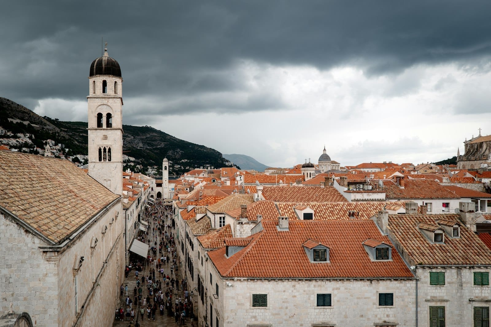 Nuages spectaculaires au-dessus de la vieille ville de Dubrovnik avec des toits orangés et des rues désertes, reflétant une atmosphère hivernale plus calme.