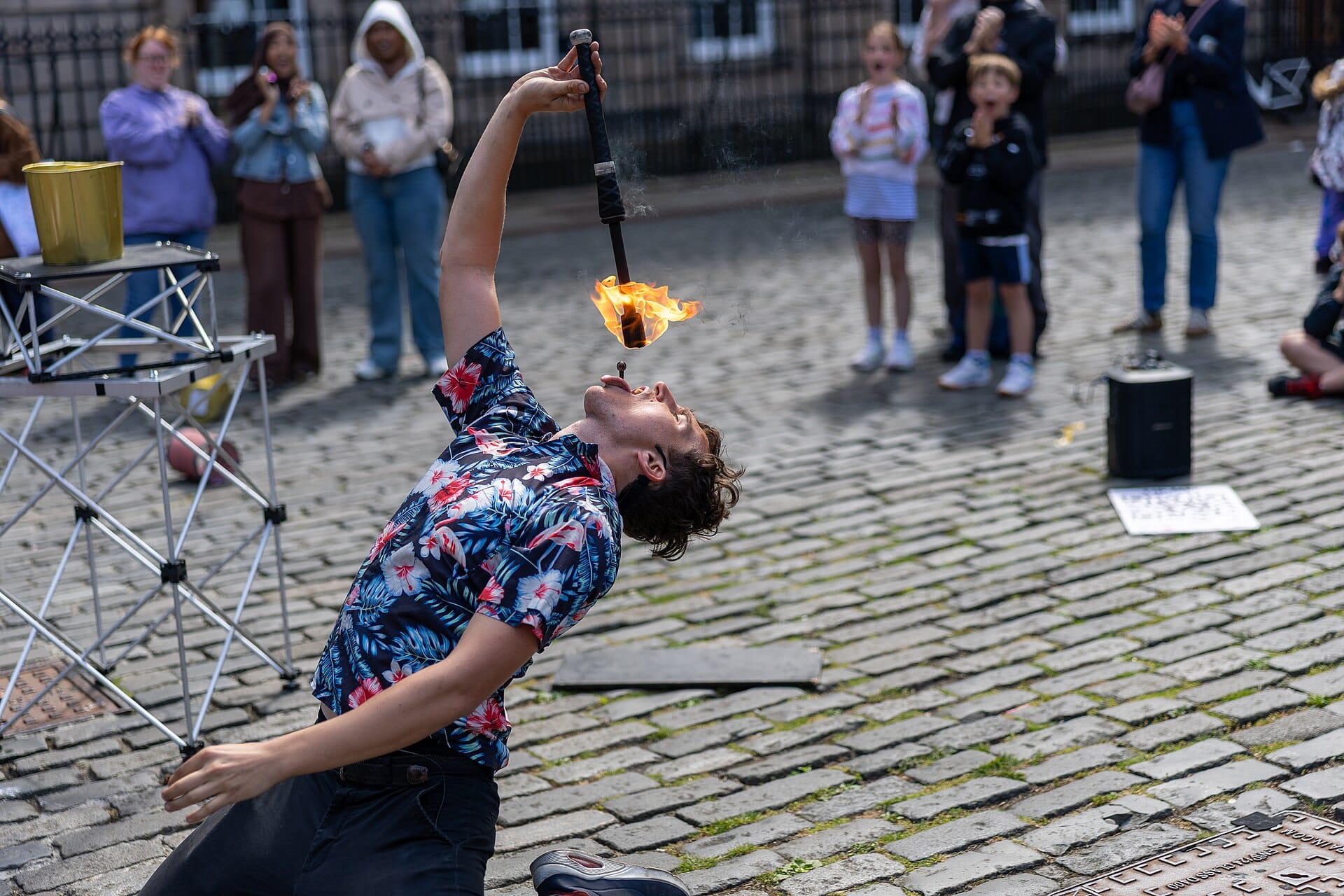 Artiste de rue crachant du feu devant un public sur une rue pavée, capturant l'atmosphère de festival au cœur d'Edinburgh.