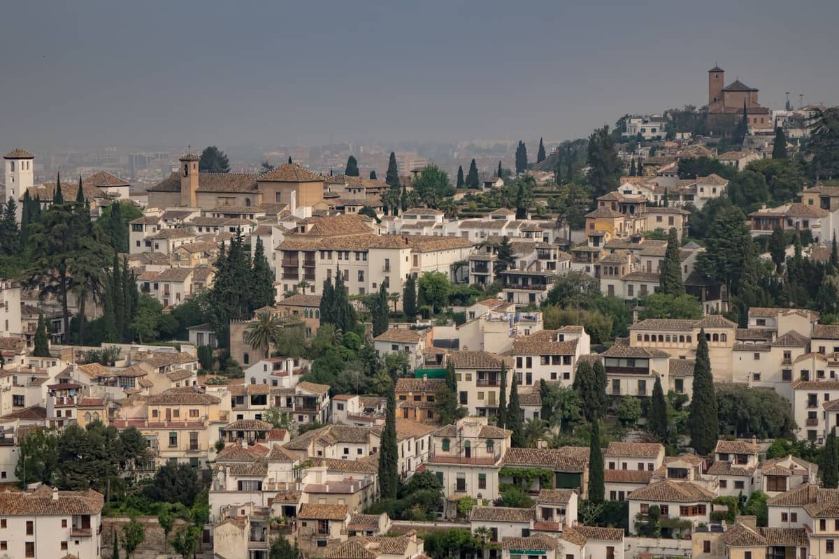 วิวทิวทัศน์ของย่าน Albaicín ในเมือง Granada พร้อมบ้านทาสีขาว ต้นไซเปรส และแสงฤดูใบไม้ร่วงอ่อนๆ บนเนินเขาประวัติศาสตร์