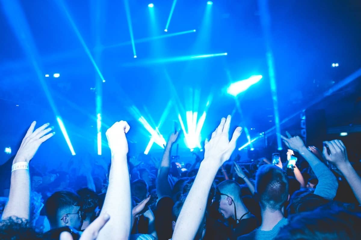 Crowd of people dancing with blue stage lights in a club, capturing the party atmosphere typical of Ibiza nightlife.