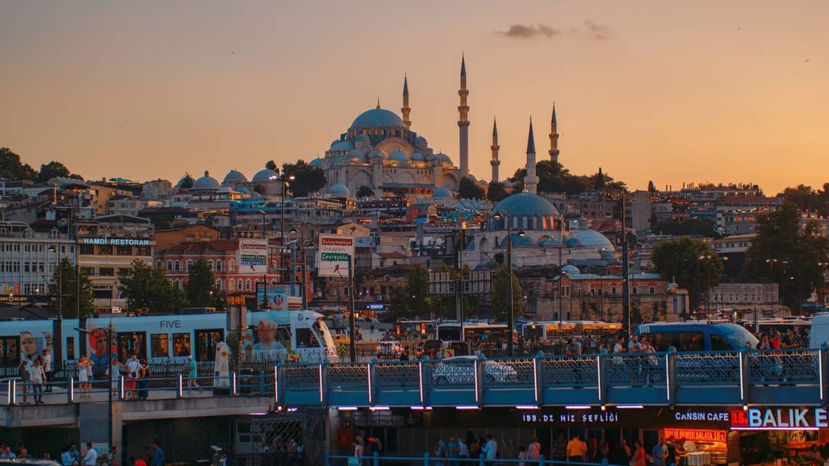 Vista dello skyline di Istanbul con una moschea, un vivace lungomare e folla durante un vibrante tramonto estivo.