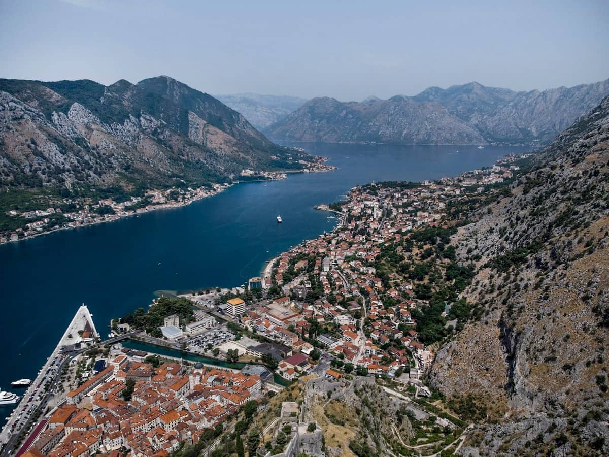 Aerial view of Kotor bay showing the old town, surrounding mountains, and waterfront, illustrating both the climate and spatial crowd patterns.