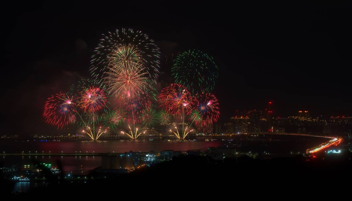 Bunte Feuerwerke erhellen den Nachthimmel über der Skyline und dem Uferbereich von Macau und deuten auf ein festliches Ereignis oder eine Feier hin.