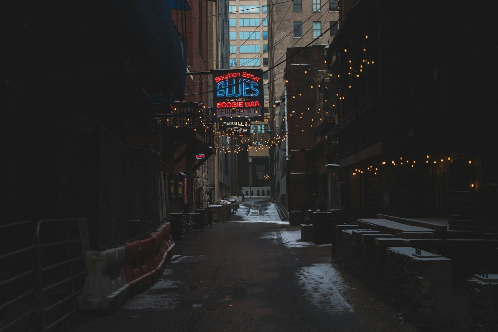 Un tranquilo callejón de Nashville con letreros de neón de bares de blues y una ligera nevada en el suelo, creando una atmósfera invernal y de temporada baja.