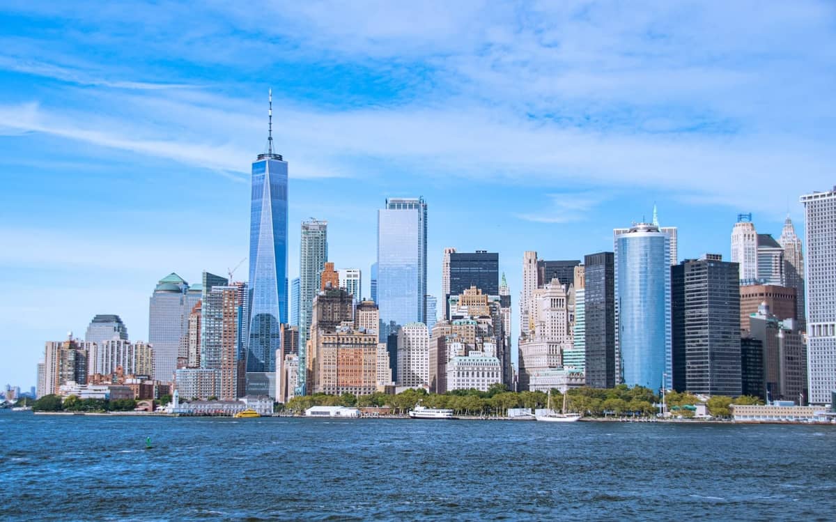 Tagesansicht der Skyline von Lower Manhattan in New York City mit klarem blauem Himmel und dem Hudson River im Vordergrund.