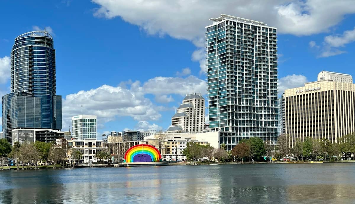 Skyline der Innenstadt von Orlando mit Lake Eola, sonnigem blauem Himmel und der markanten Regenbogen-Bandmuschel