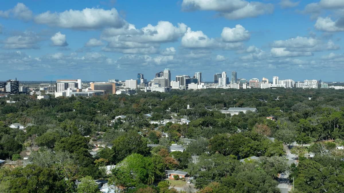 Skyline von Orlando mit vereinzelten Wolken über einem weitläufigen Vorort- und Stadtgebiet an einem hellen Tag