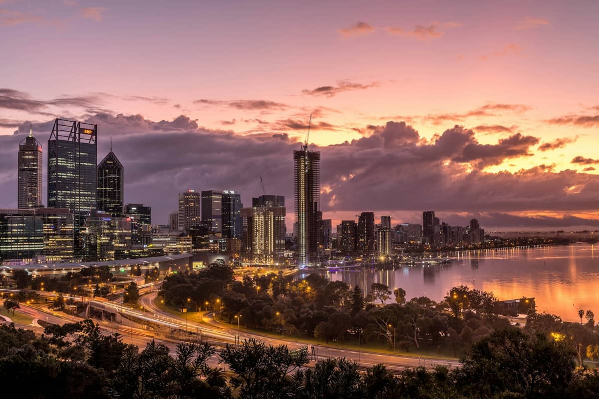Lo skyline di Perth al tramonto con il fiume Swan, grattacieli, un cielo colorato e i loro riflessi sull'acqua, in Australia Occidentale.