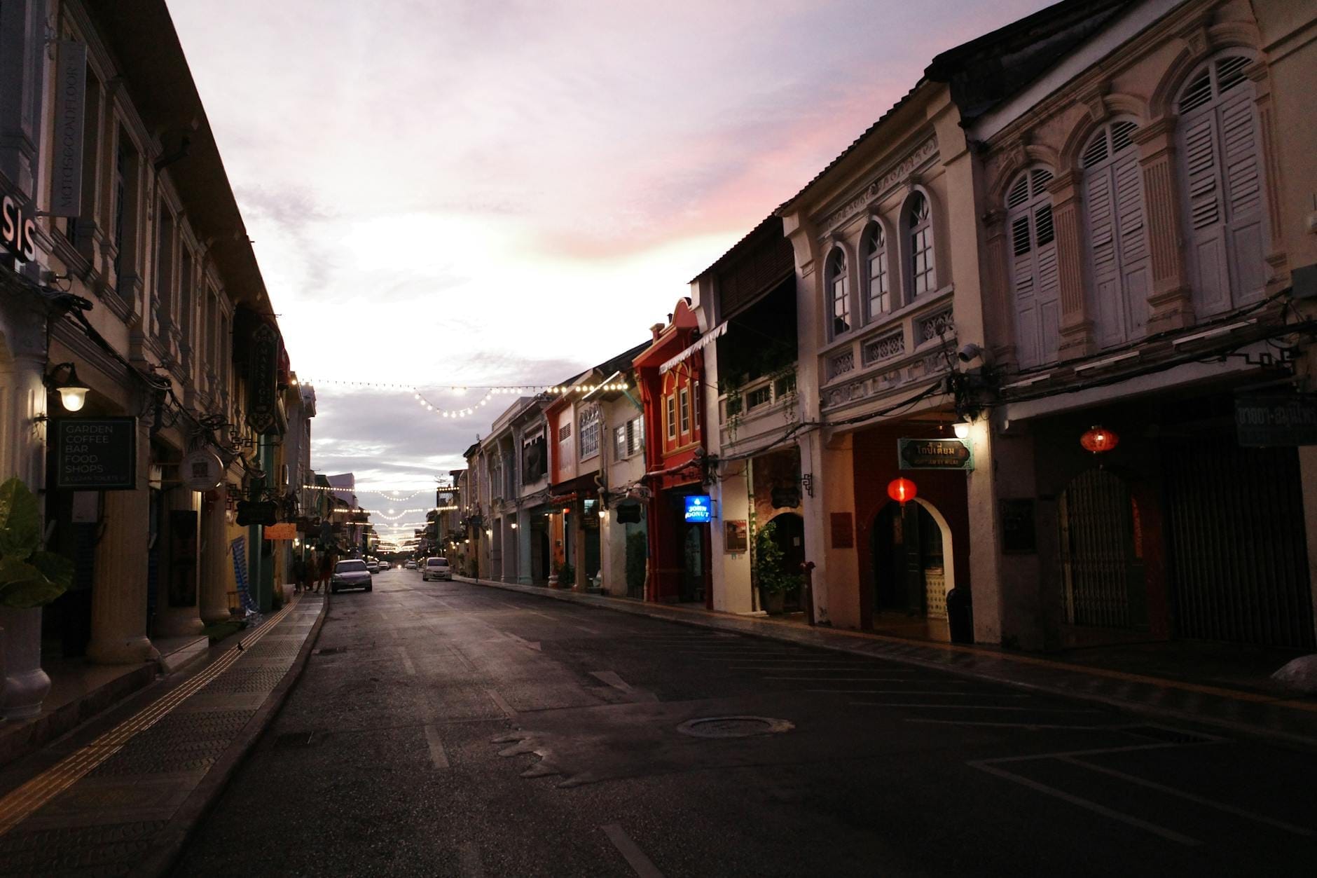 Empty Old Town Phuket street at dusk with colorful Sino-Portuguese shophouses and a soft, overcast sky during shoulder season.