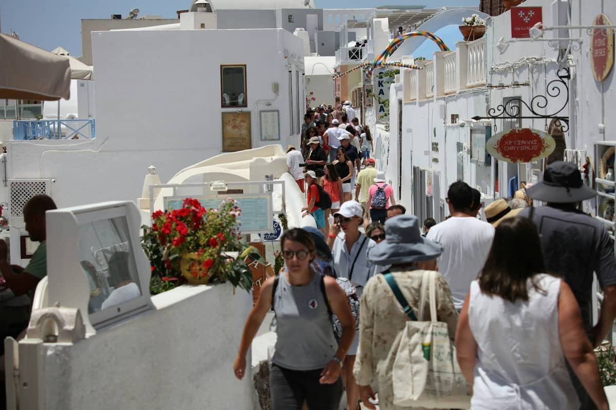 Menschenmassen, die an einem sonnigen Tag durch die engen, weiß getünchten Gassen von Santorini schlendern