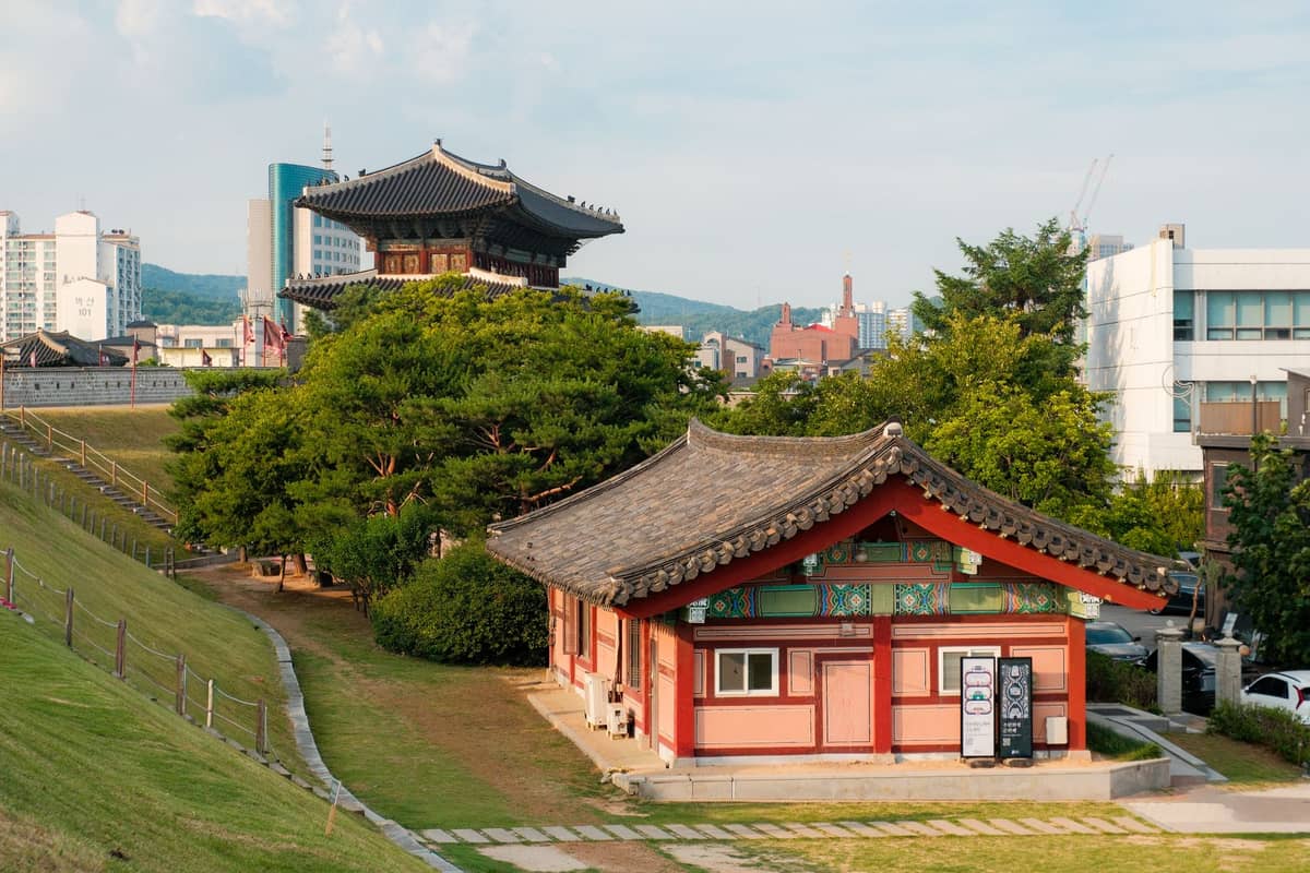 Edifícios coreanos tradicionais ao lado de um horizonte moderno em Seul em um dia claro, destacando tanto o patrimônio quanto o ambiente urbano da cidade.