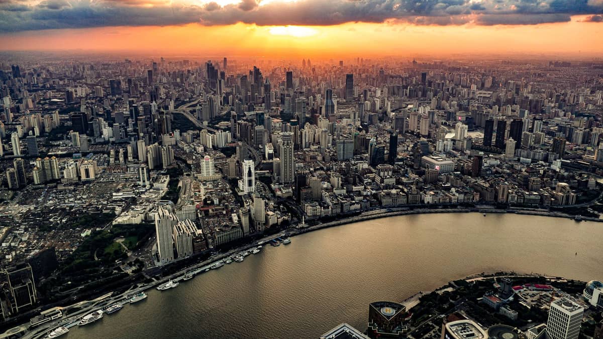 Luftaufnahme der Skyline von Shanghai und des Huangpu-Flusses bei Sonnenuntergang, mit der Lage der Stadt, dem Fluss und der klimarelevanten Geographie.