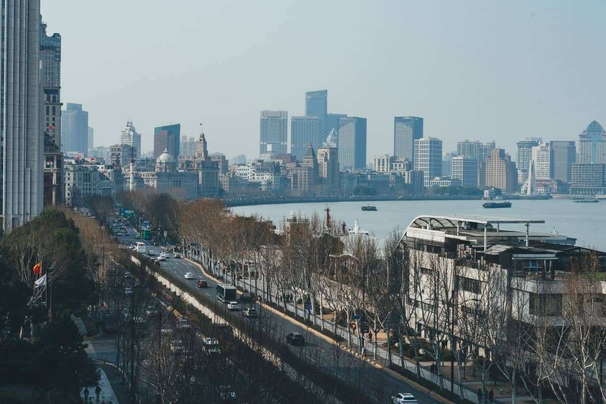 Tagesansicht des Bund in Shanghai mit kahlen Winterbäumen entlang des Flussufers, wenigen Autos und einer stimmungsvollen, kühlen Atmosphäre.