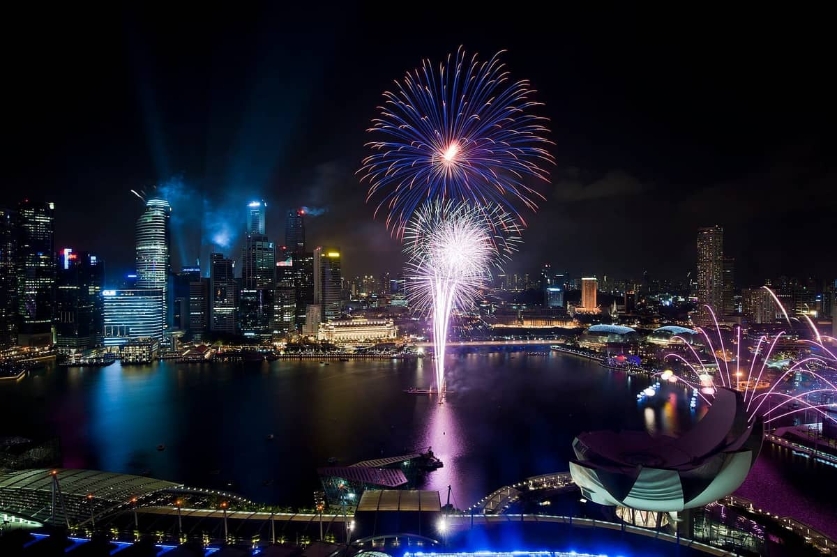 Colorful fireworks explode over Marina Bay, highlighting Singapore’s illuminated skyline and waterfront landmarks during a vibrant night celebration.