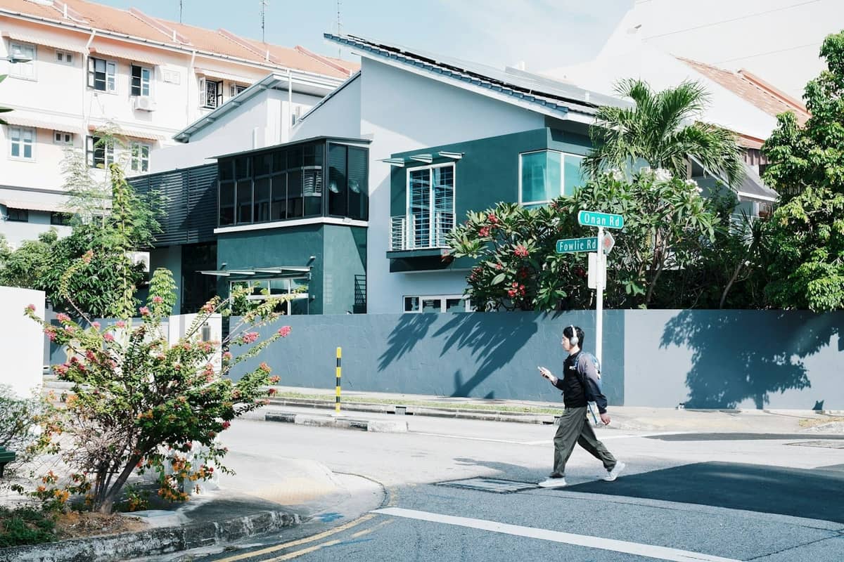 Modern houses and tropical greenery line the intersection of Onan Road and Fowlie Road in a sunny Singapore neighborhood.