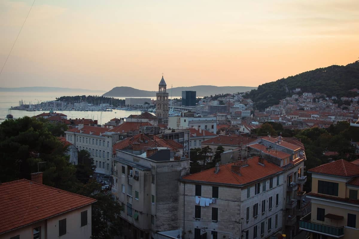 Blick über Split zur goldenen Stunde, mit Glockenturm, Terrakotta-Dächern, der Adria und fernen Hügeln unter einem sanften Herbsthimmel.